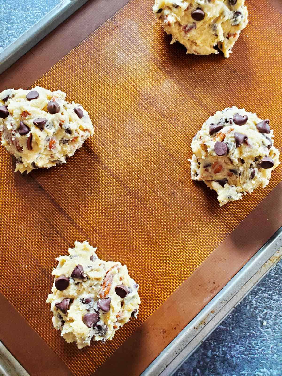 four large balls of cookie dough with chocolate morsels studded on the top.