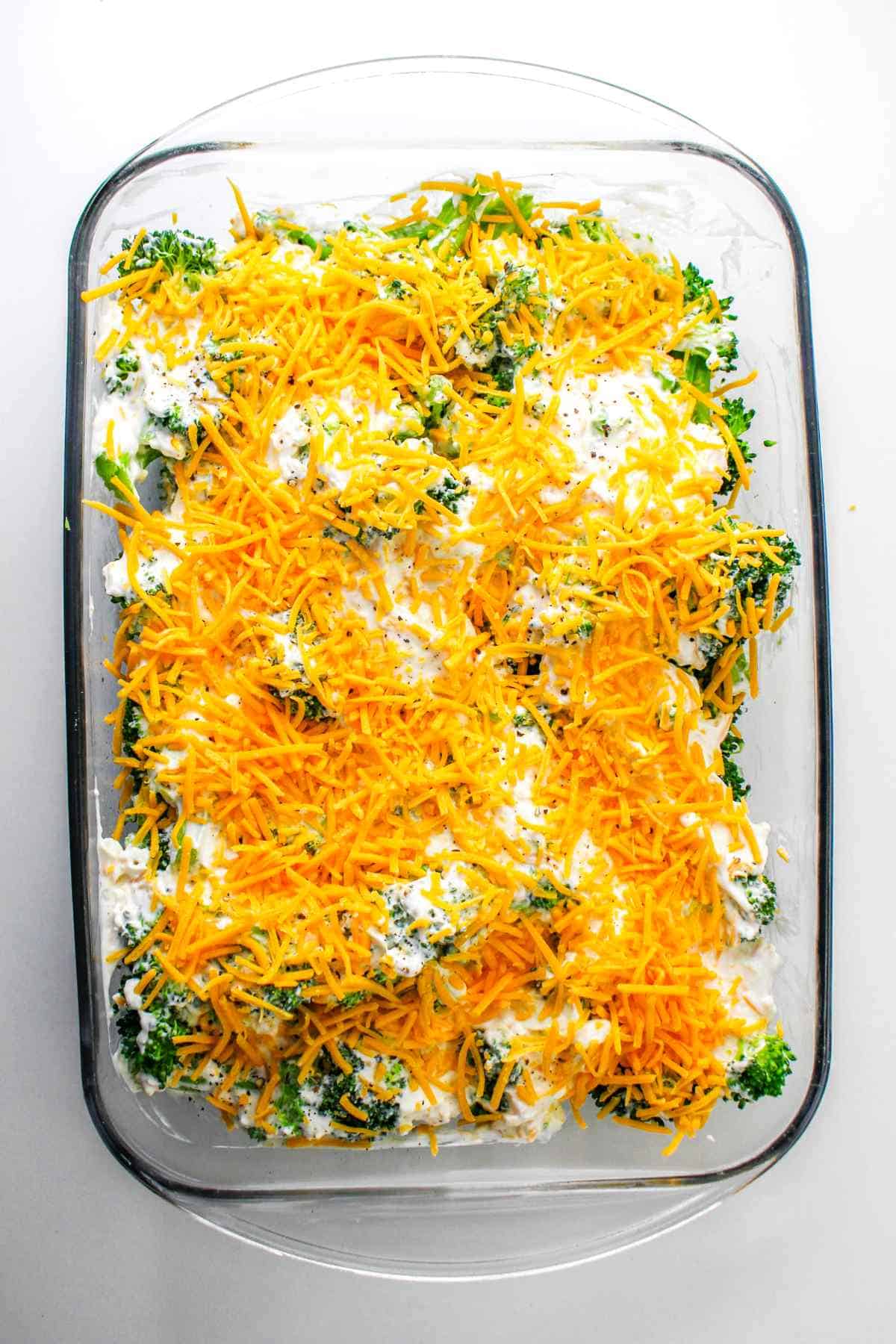 layered broccoli casserole with cheddar cheese on top.