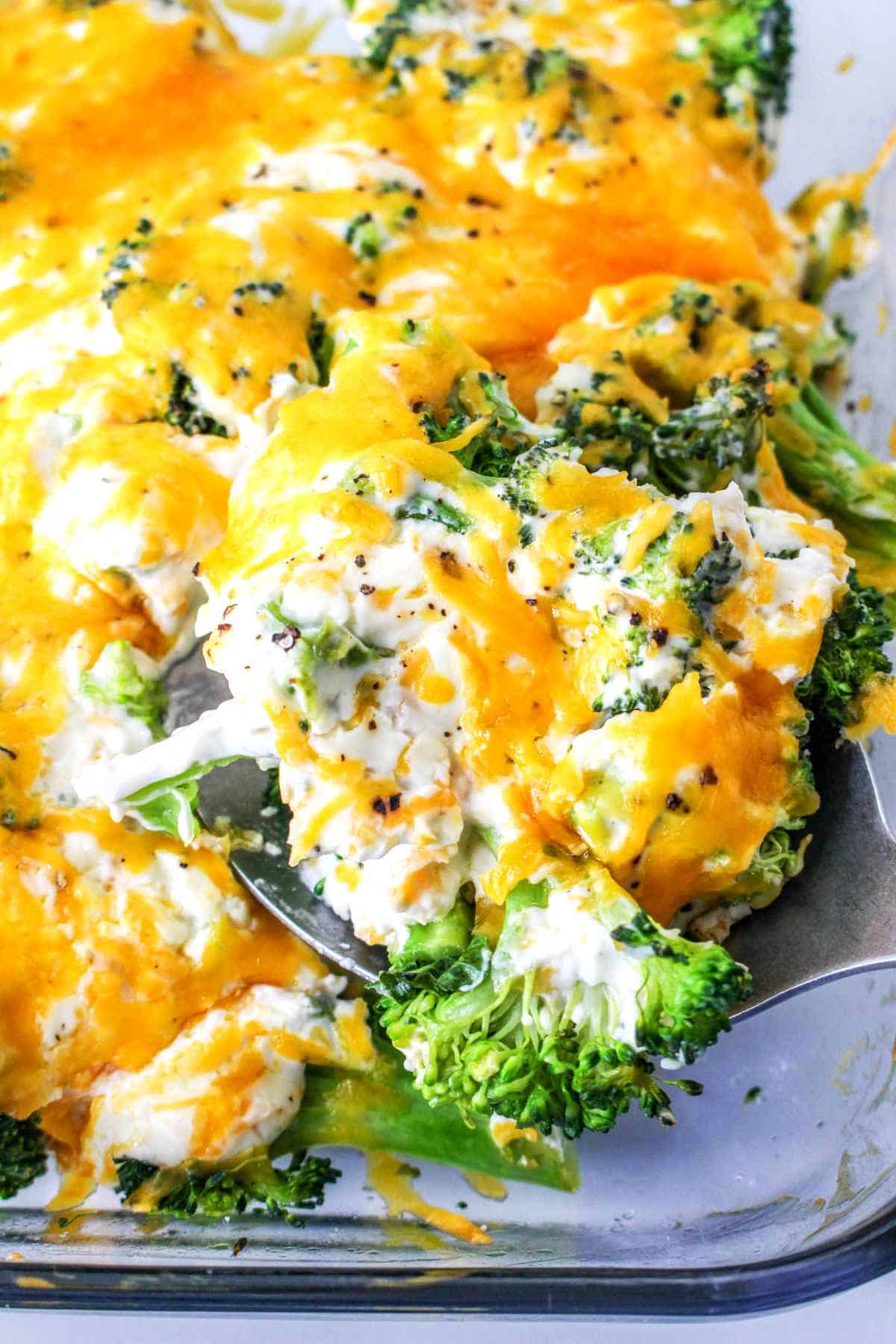 Baking dish with a scoop of broccoli and creamy cheese being served from.
