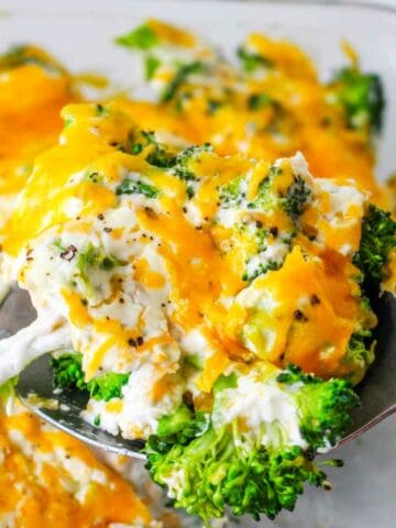 Baking dish with a scoop of broccoli and creamy cheese being served from.