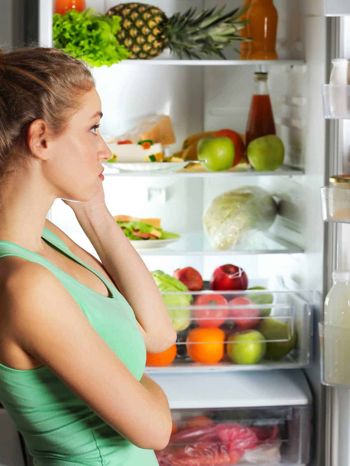 A mom looking into fridge to plan a meal.