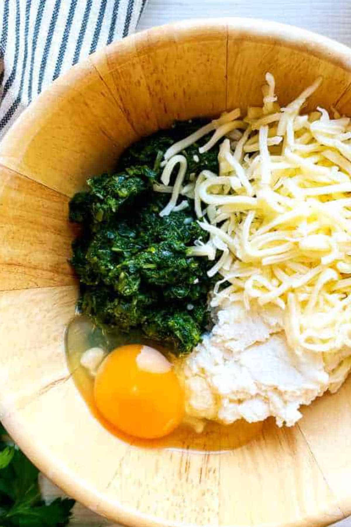 egg, spinach, ricotta, and grated parmesan in a bowl.