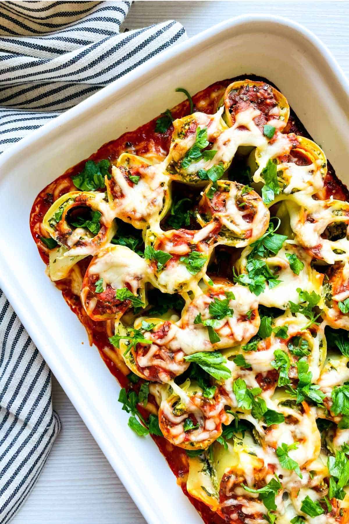 baked spinach ricotta lasagna roll ups in a casserole dish.