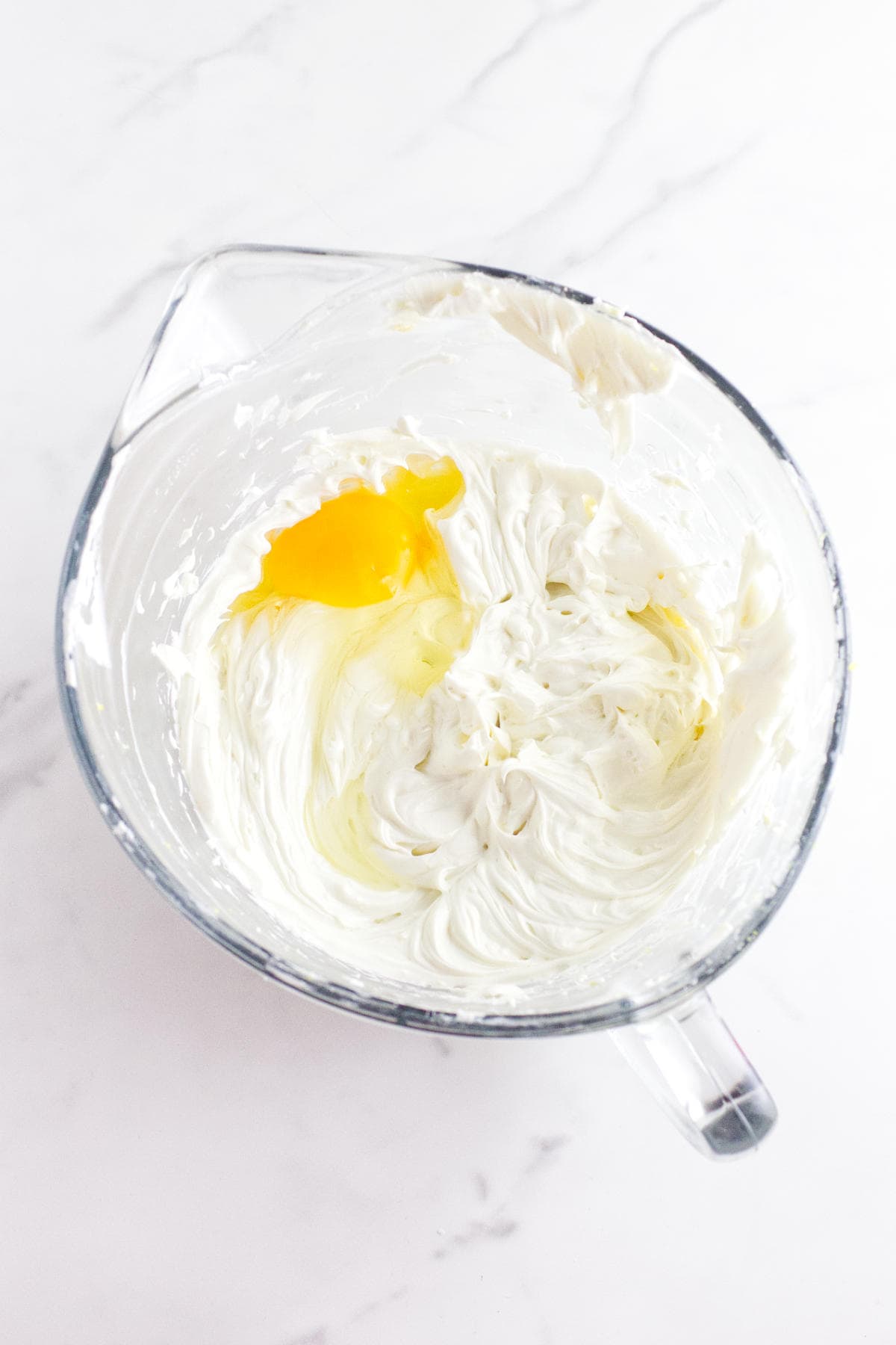 eggs added to cream cheese in a mixing bowl.