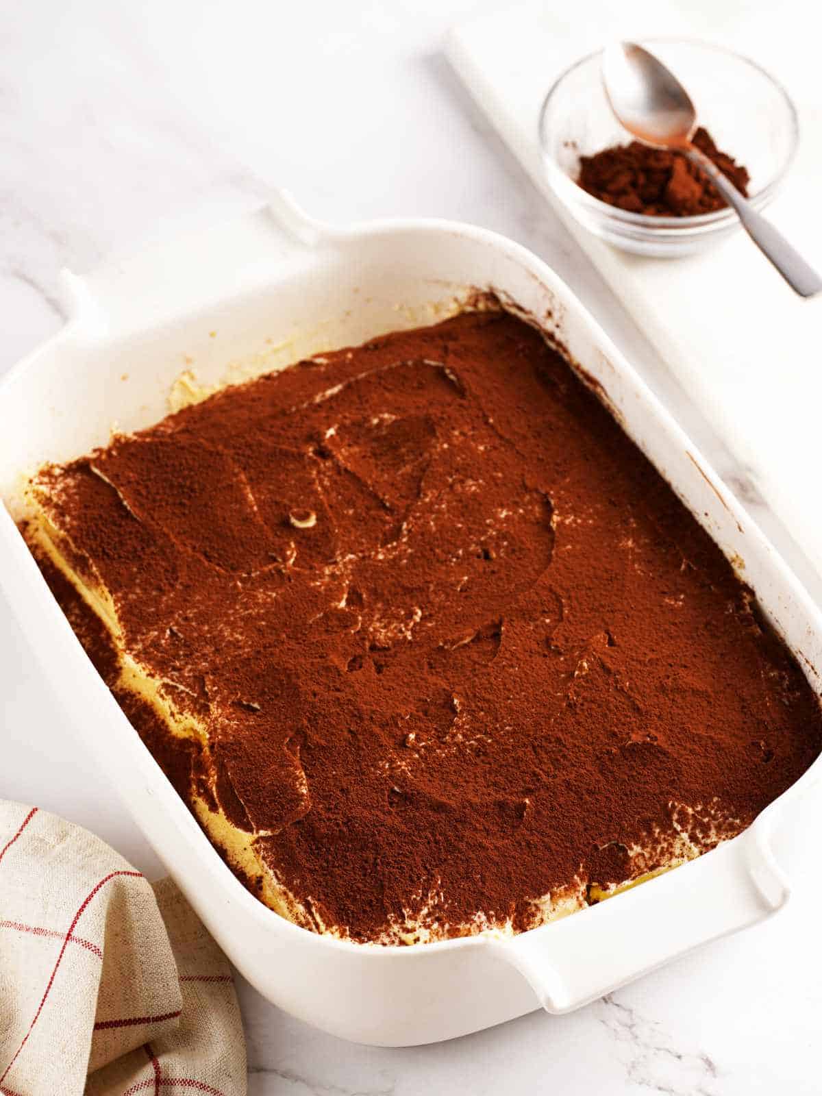 baking dish filled with cocoa powder dusted Italian dessert.
