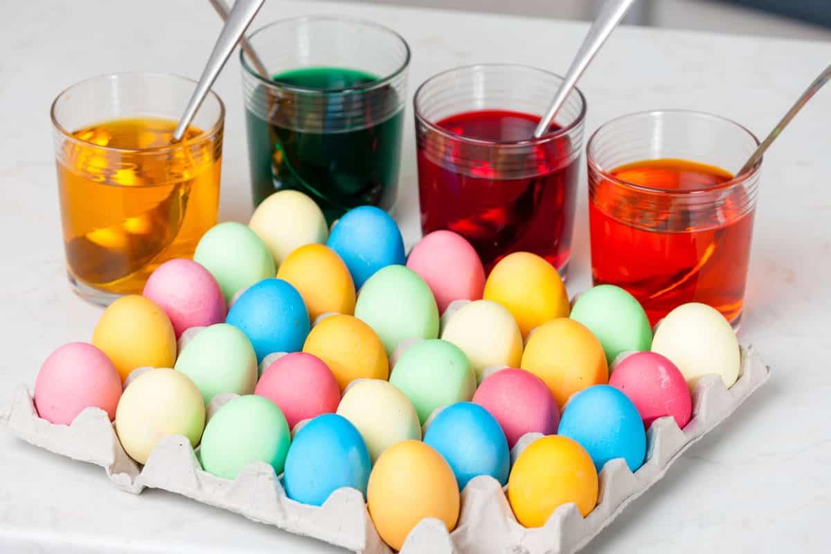 dyed Easter eggs in a paper tray drying. Jars of egg dye solution nearby.