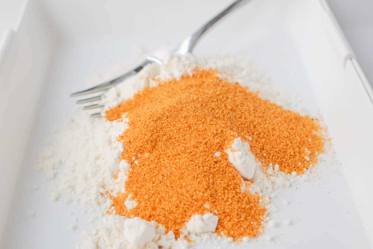 flour and seasoning salt being mixed in a bowl.