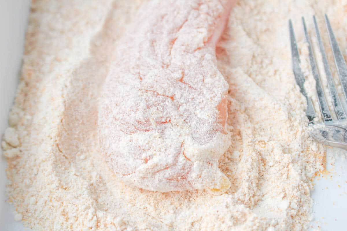 seasoned flour on raw chicken tender.