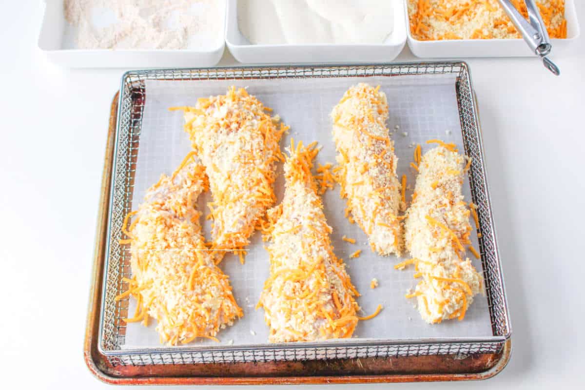 Cheddar Ranch coated chicken tenders laid on an air fryer tray.