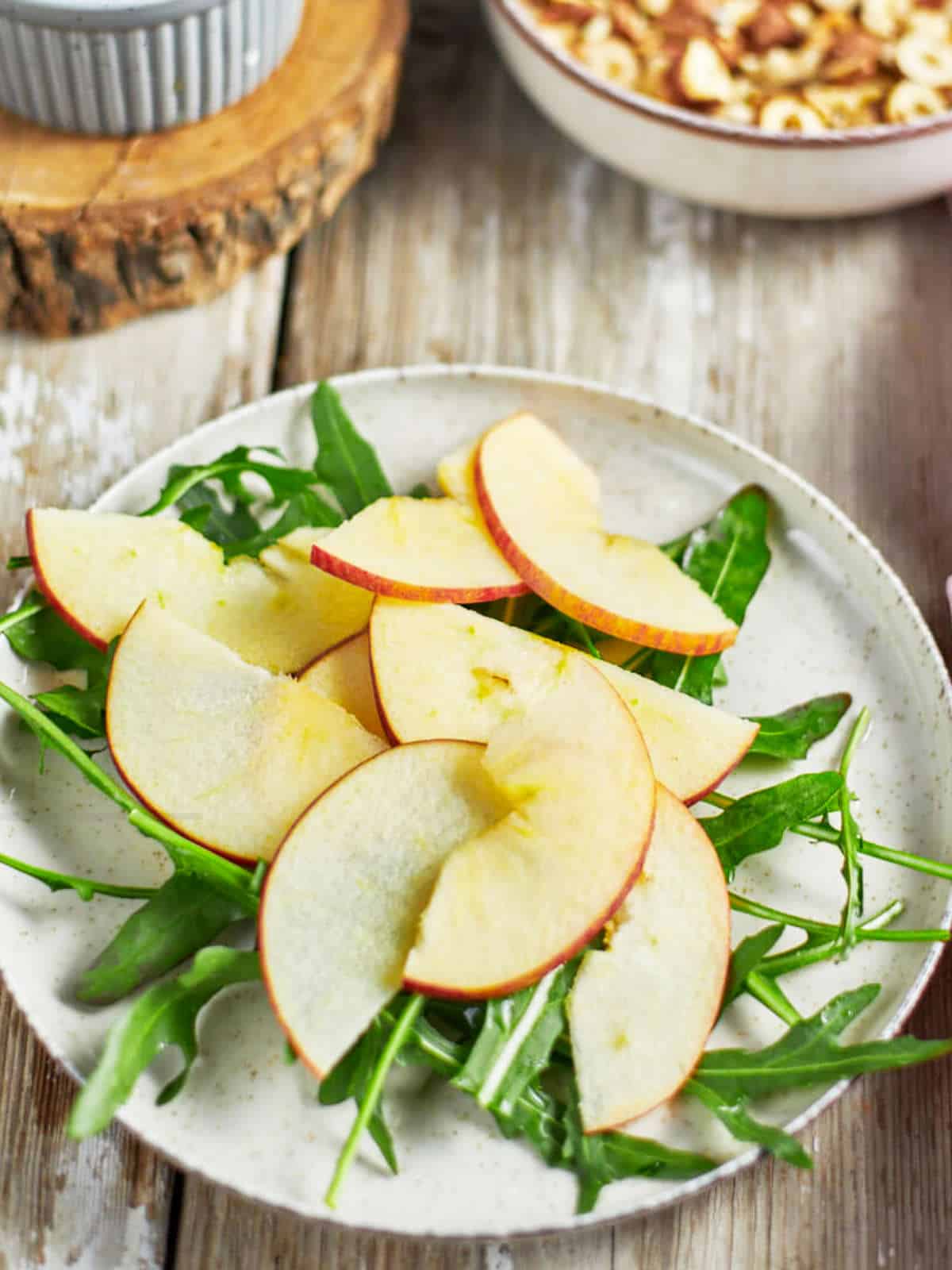 Thinly sliced apples on top of arugula leaves.