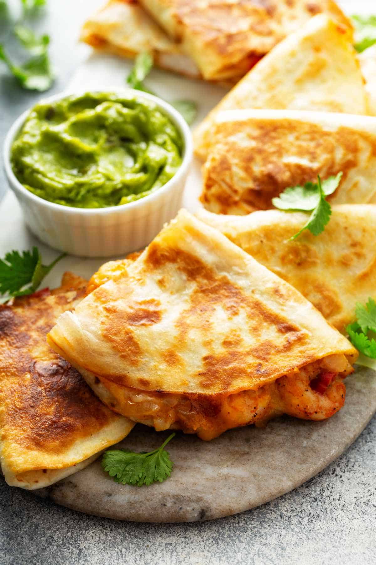 Shrimp and cheese quesadillas with red pepper and cilantro served with guacamole.