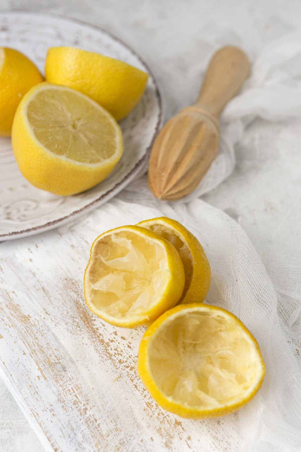Wooden citrus reamer and juiced lemons.