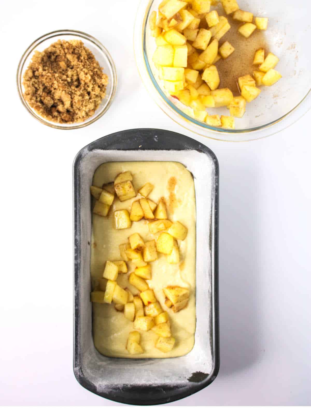 half the cinnamon apples added to the loaf pan on top of the cake batter.