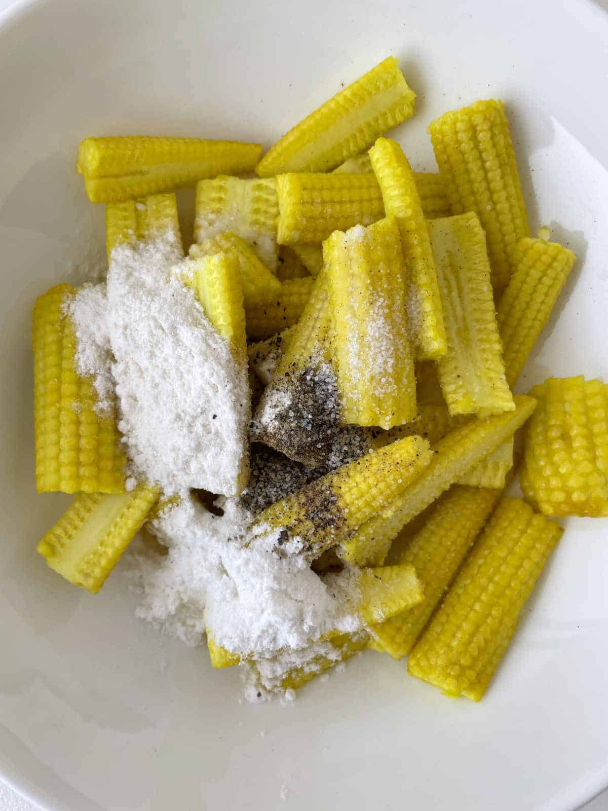 boiled baby corn with cornstarch and seasoning in a bowl.