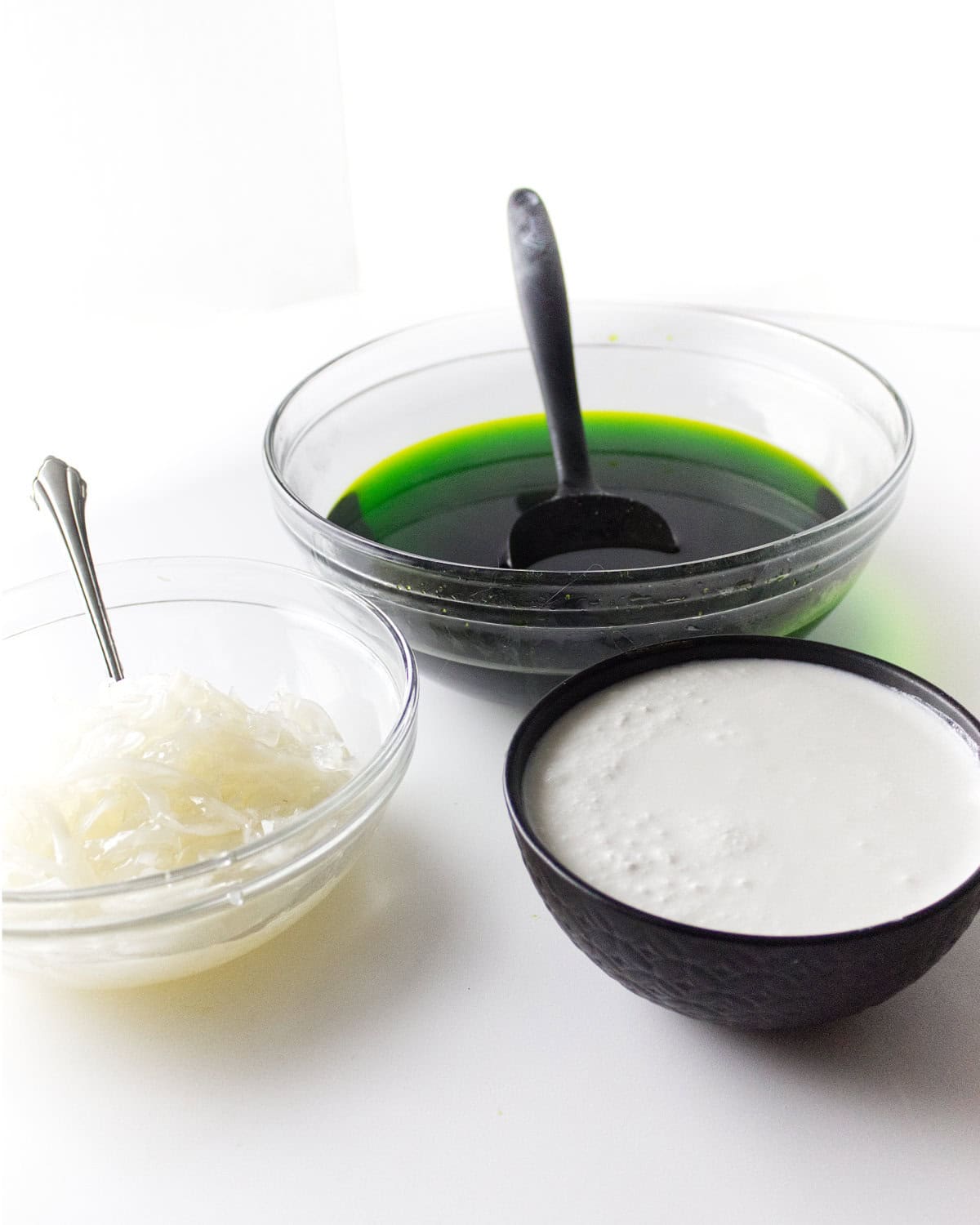 bowl of green jello, coconut milk, and a bowl of sport coconut.