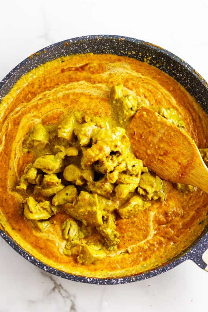 Chicken added to butter chicken sauce.