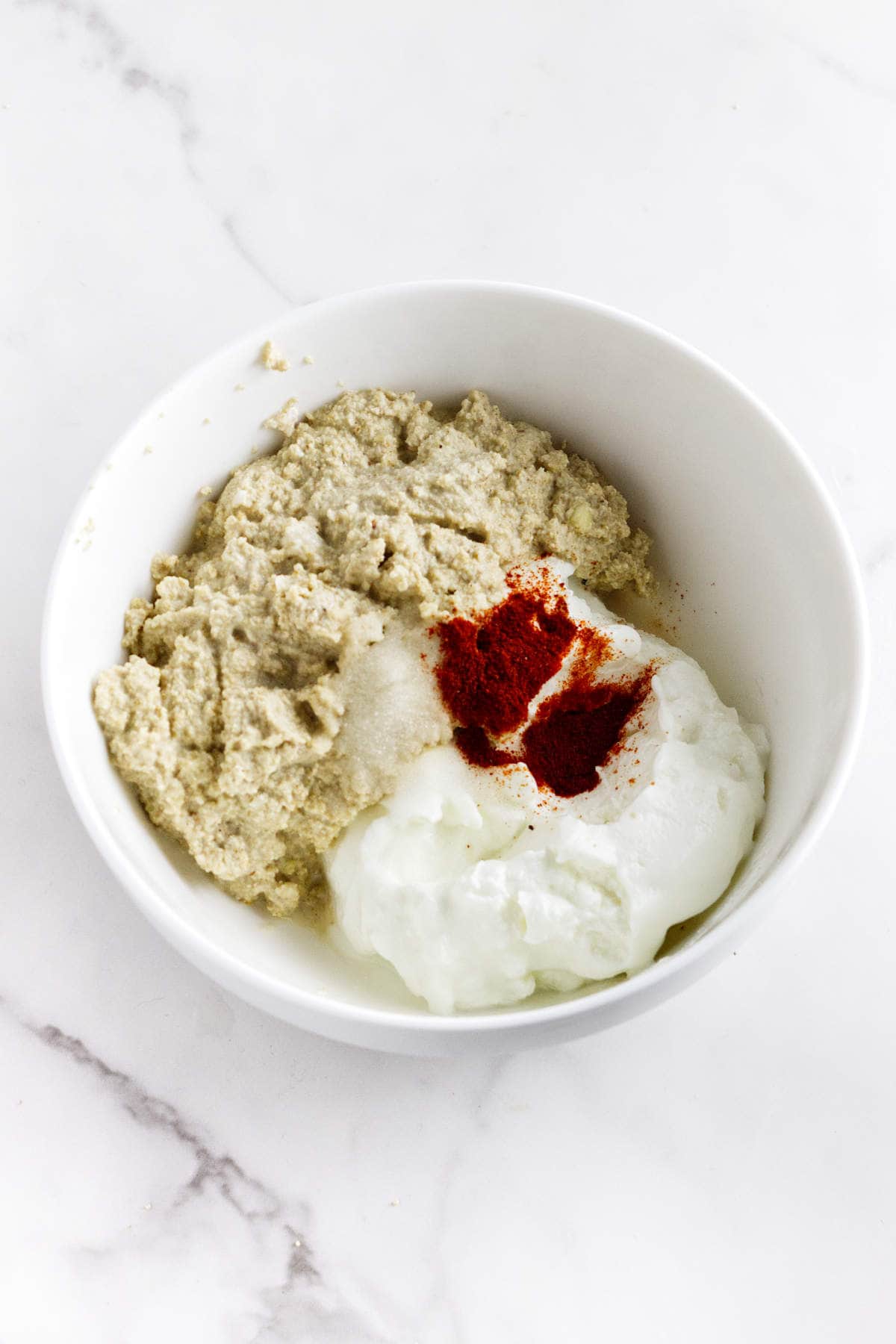 Ground cashew and white poppy seeds with yogurt and spices in a bowl.