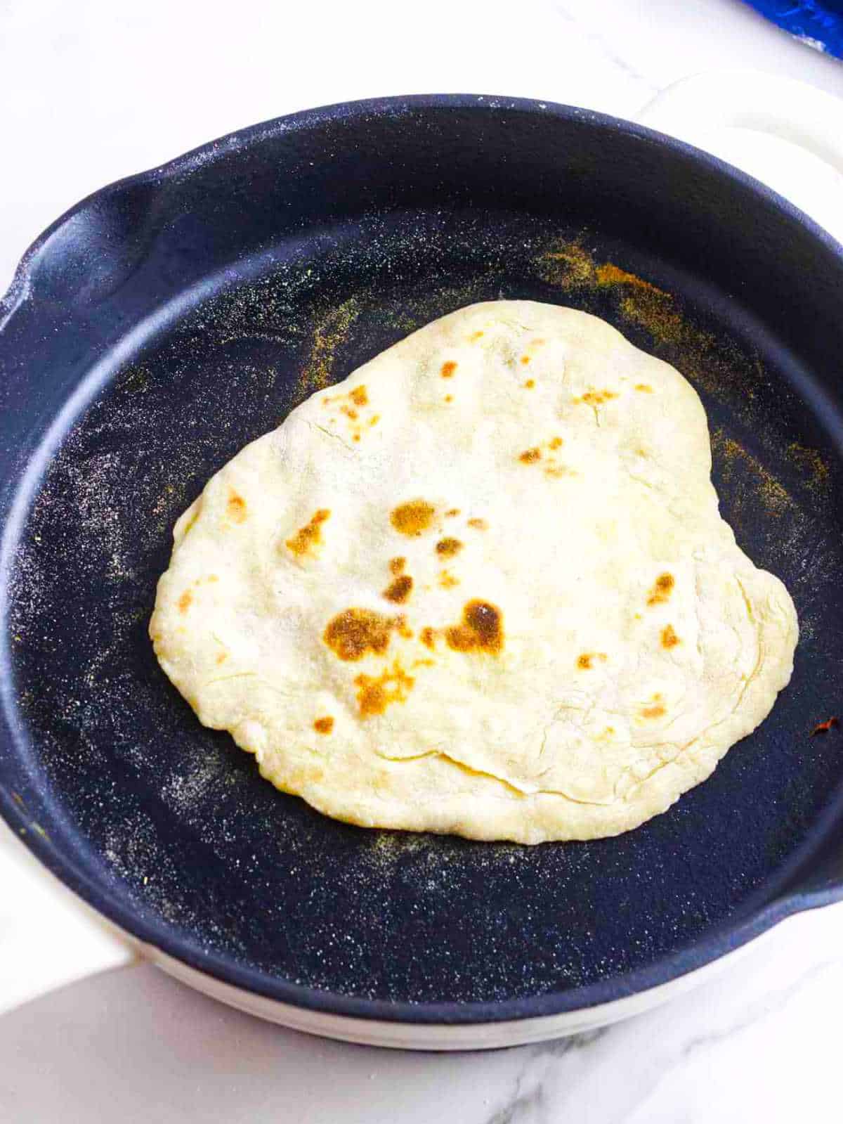 frying naan bread in a hot skillet.