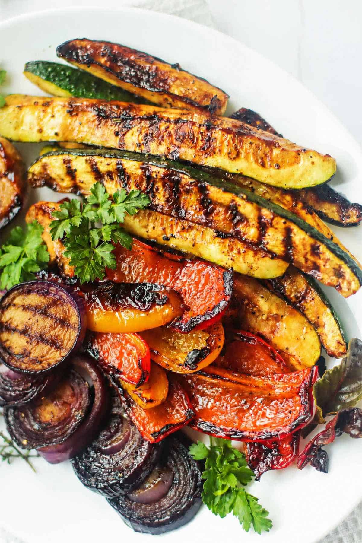 Grilled Mediterranean vegetables with zucchini, bell peppers, red onion, eggplant, and parsley garnish.