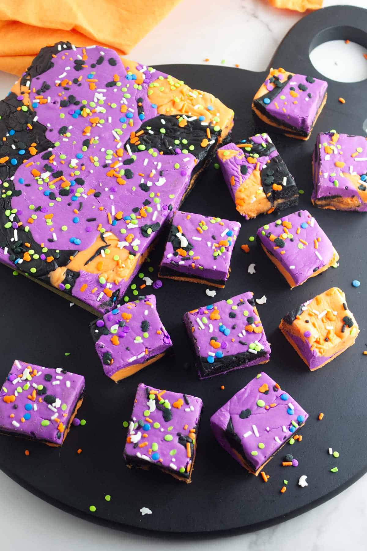 purple, orange, and black festive Halloween fudge cut into squares for serving.