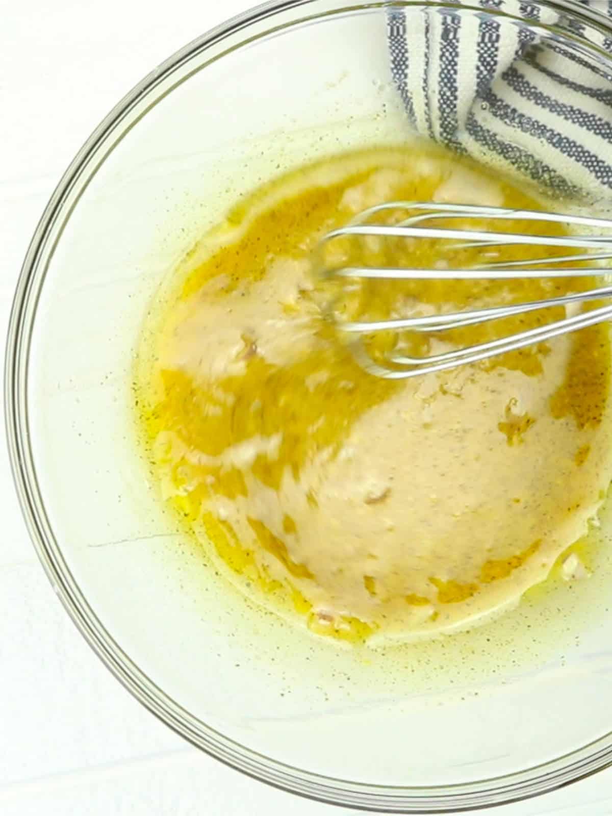 whisking olive oil, balsamic white vinegar, dijon mustard into a salad dressing.