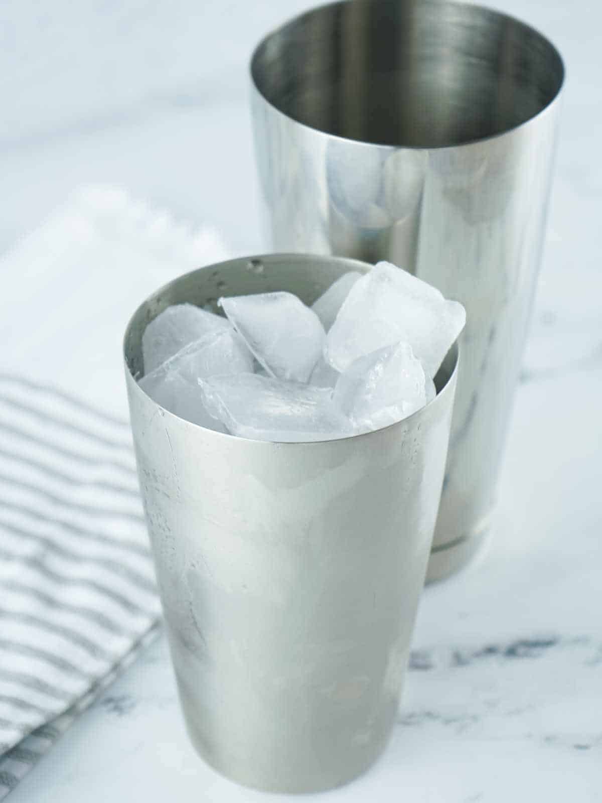 Ice added to a cocktail shaker.