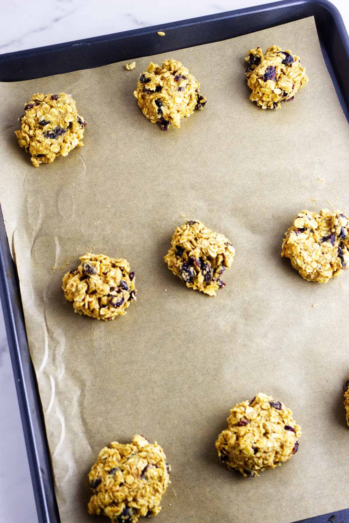 oatmeal craisin cookie dough balls on a baking sheet.