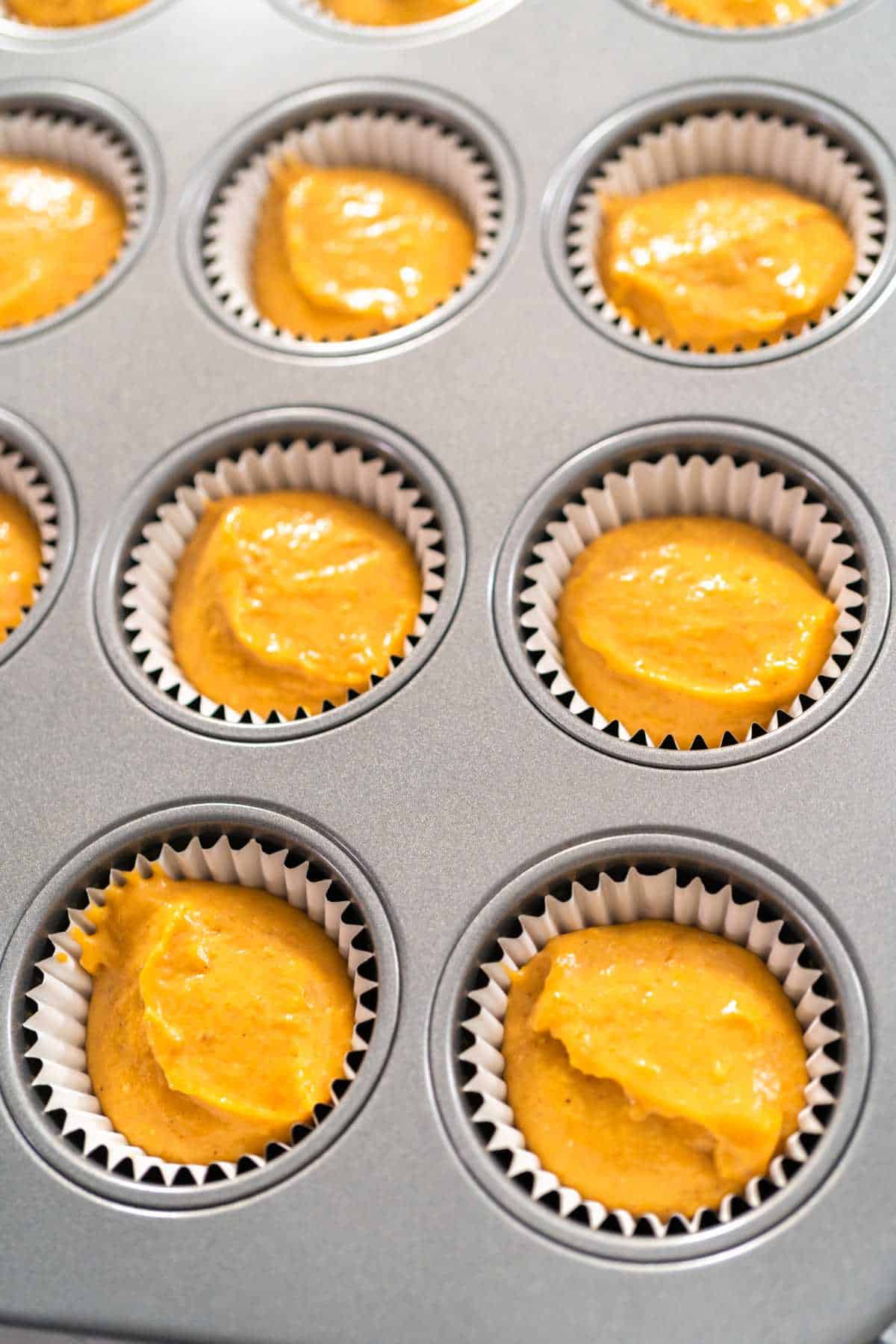 Peanut butter and pumpkin spice cupcake batter in a cupcake pan with liners.