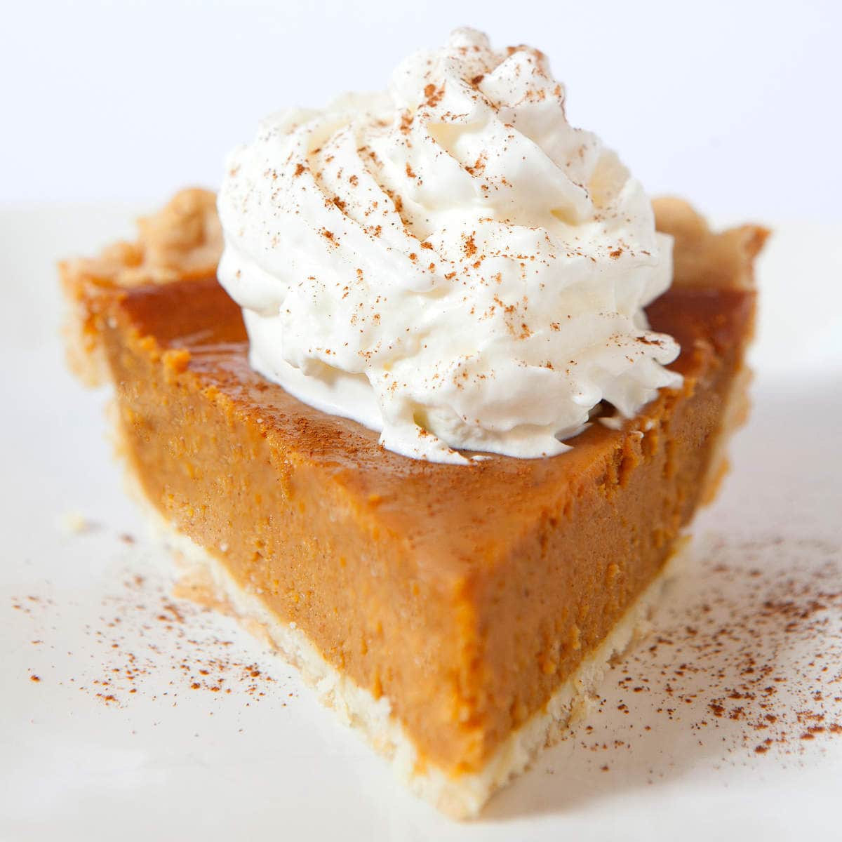 pumpkin pie without evaporated milk with whipped cream and cinnamon on top.
