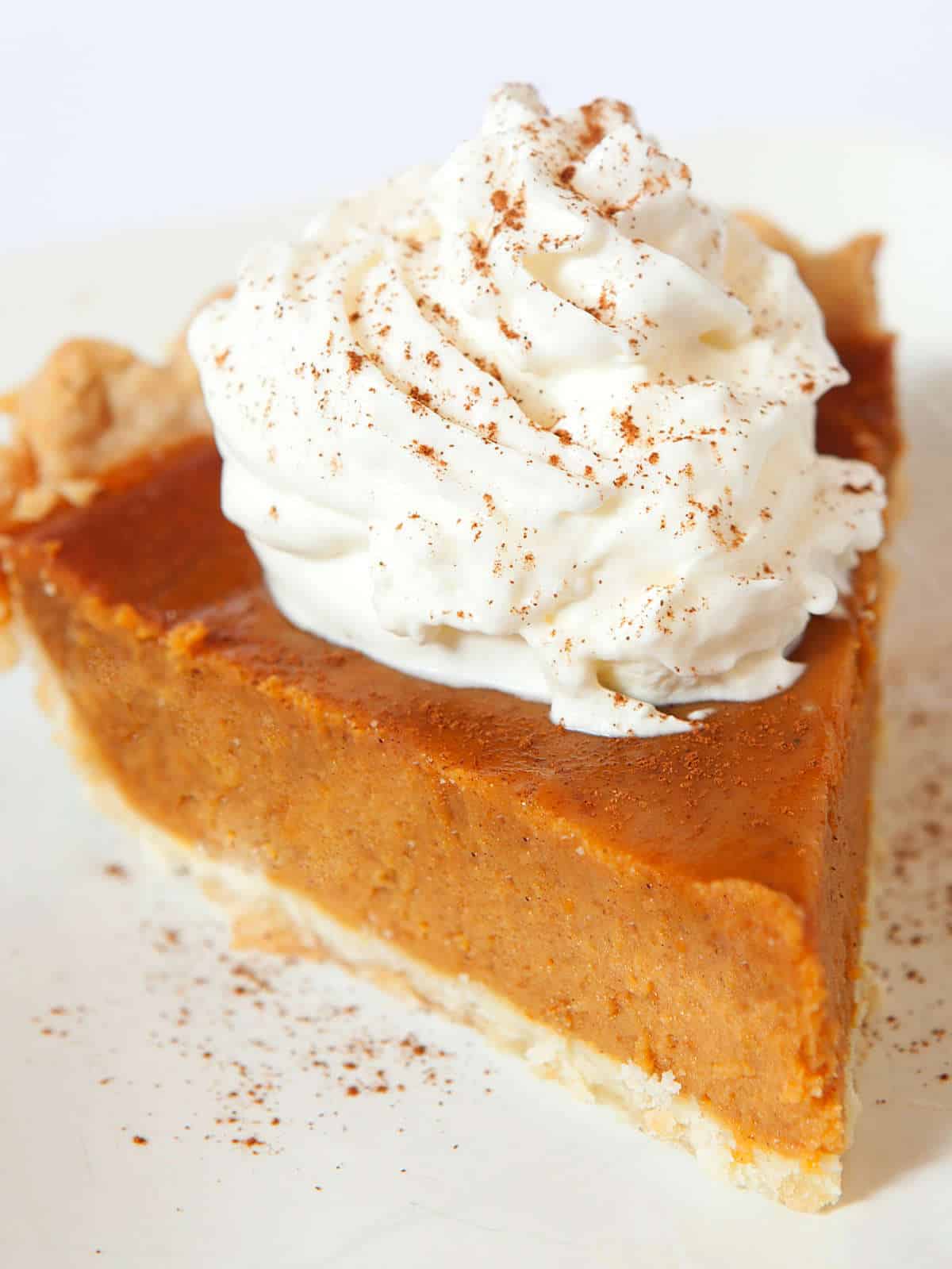 pumpkin pie without evaporated milk with whipped cream and cinnamon on top.