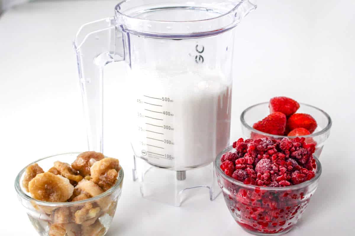 Loading a blender with milk for making a raspberry smoothie.