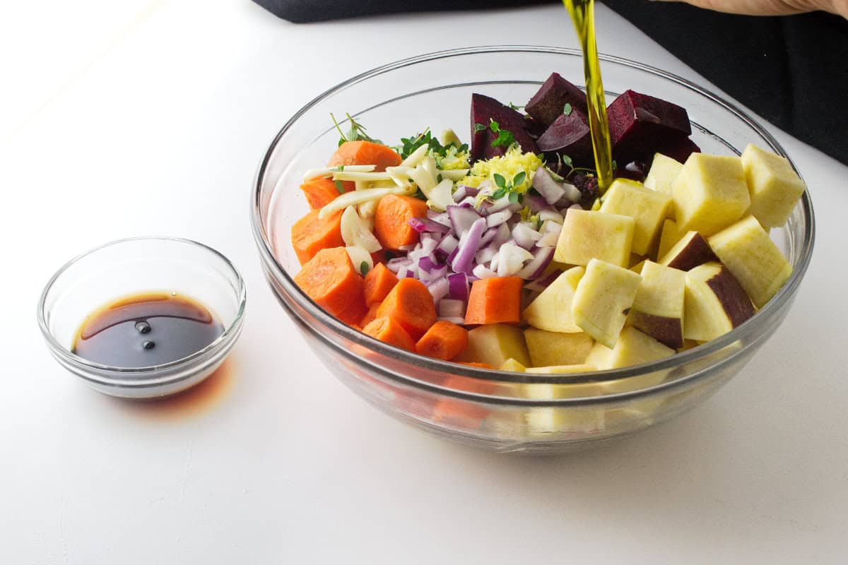 cut carrots, beets, and rutabagas in a bowl with olive oil, herbs and seasonings.