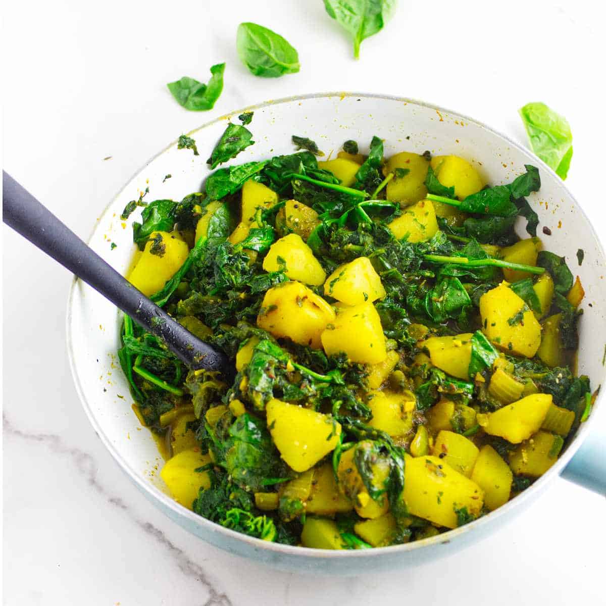Saag aloo (spinach and potato curry) in a skillet.