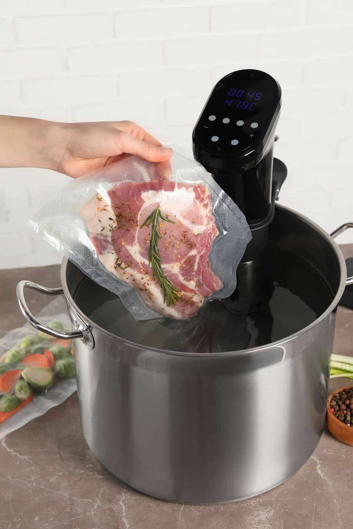 Woman putting vacuum packed meat into pot with sous vide cooker