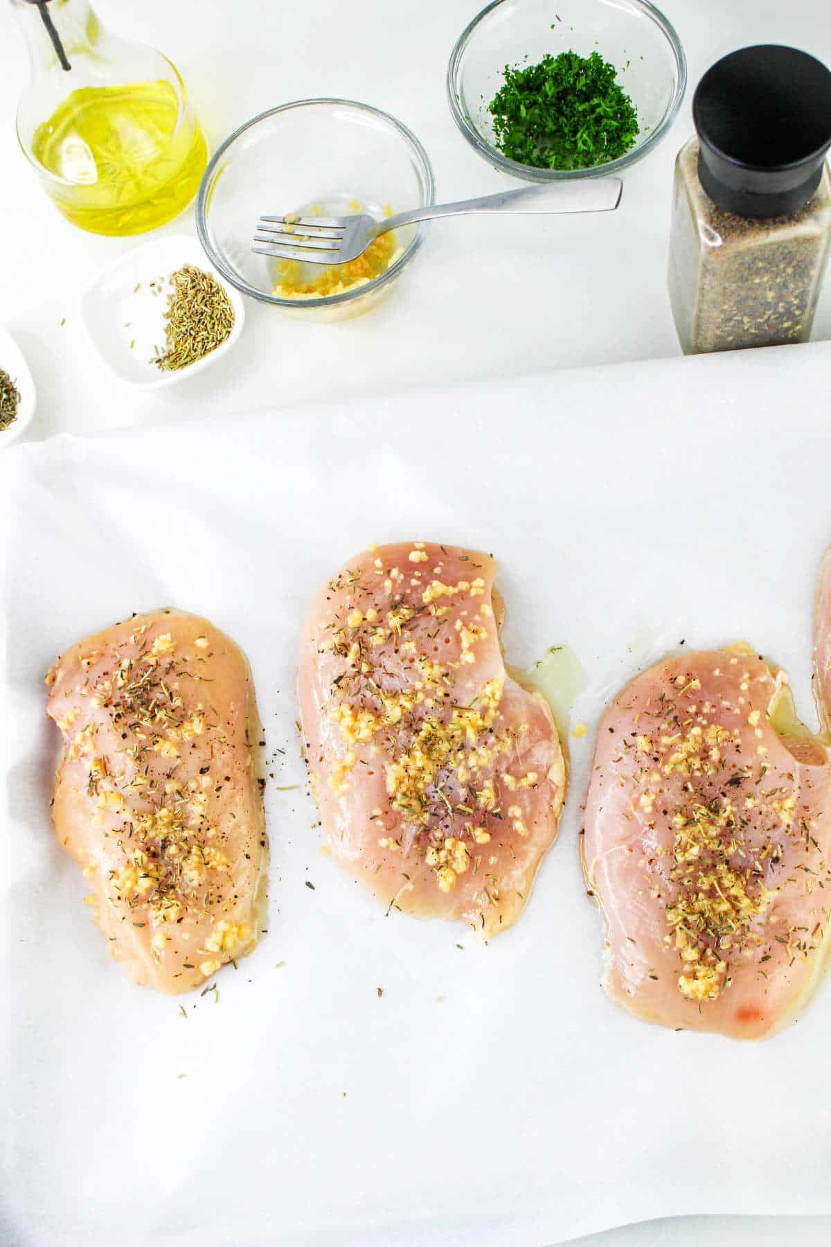 seasoned chicken breasts on a work surface.
