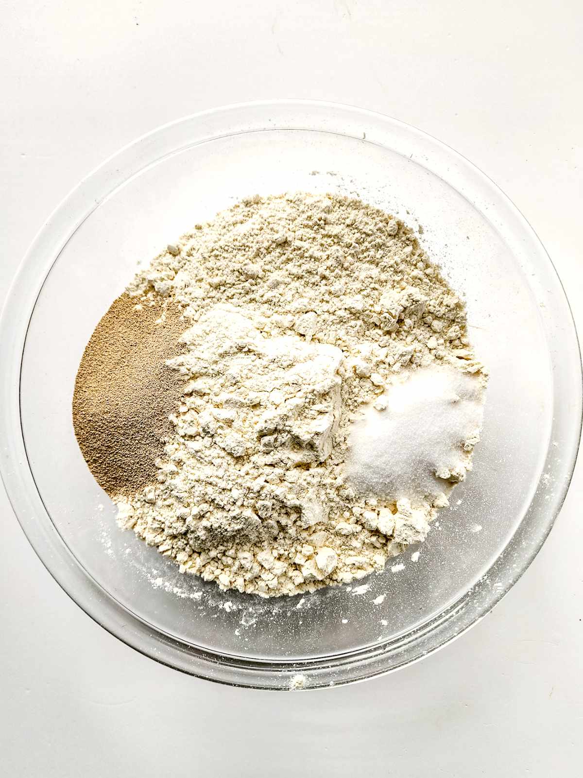 yeast and salt added to bread flour in a bowl.