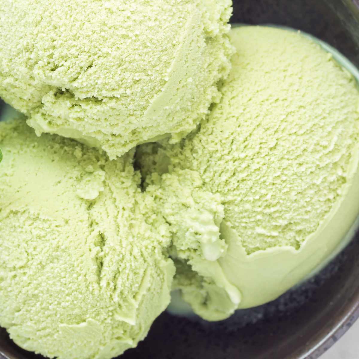 Matcha green tea ice cream balls in black bowl.