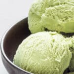 Matcha green tea ice cream balls in black bowl.