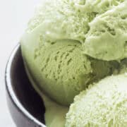 Matcha green tea ice cream balls in black bowl.