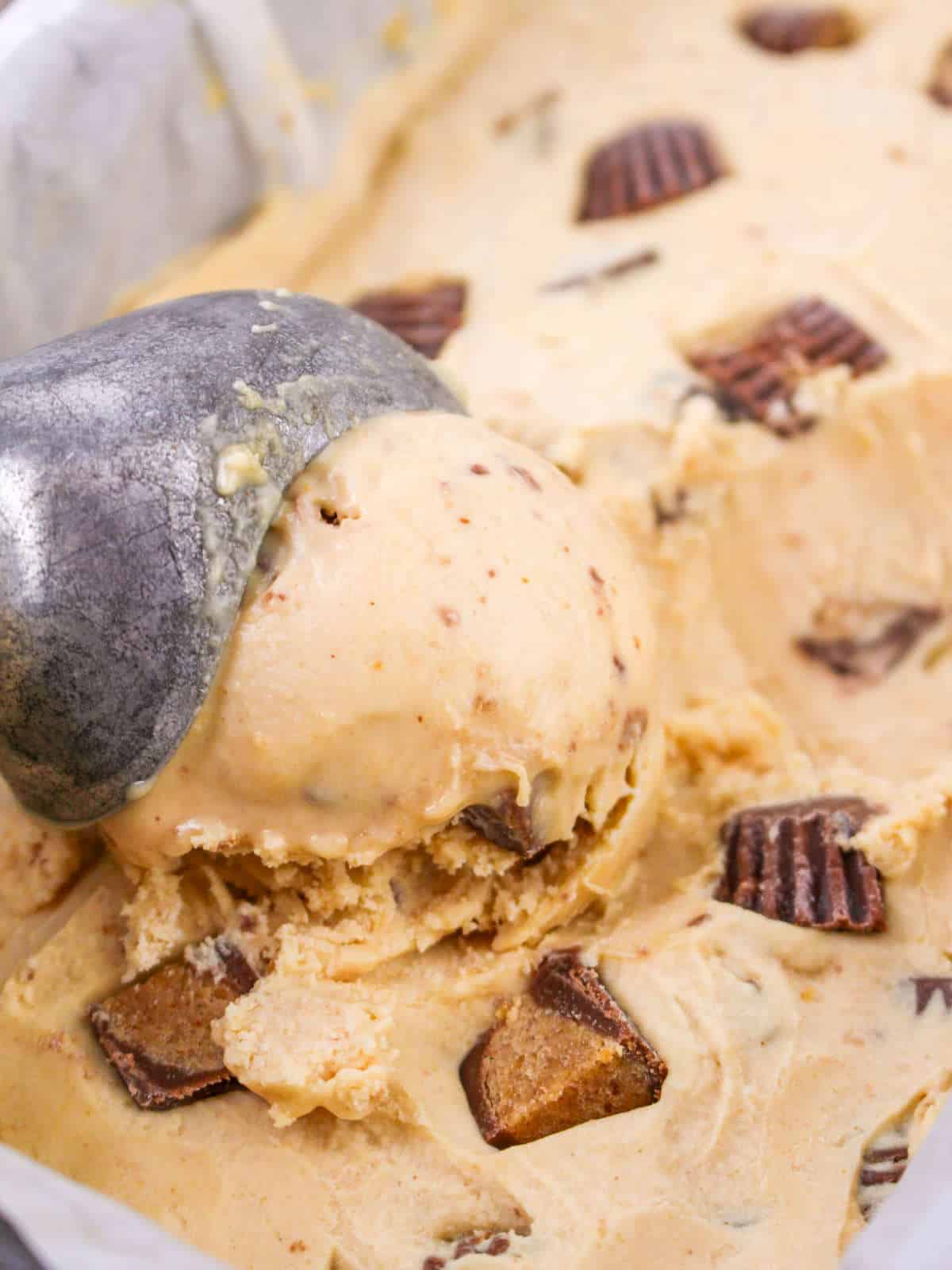 scooping peanut butter ice cream from a freezer tub.