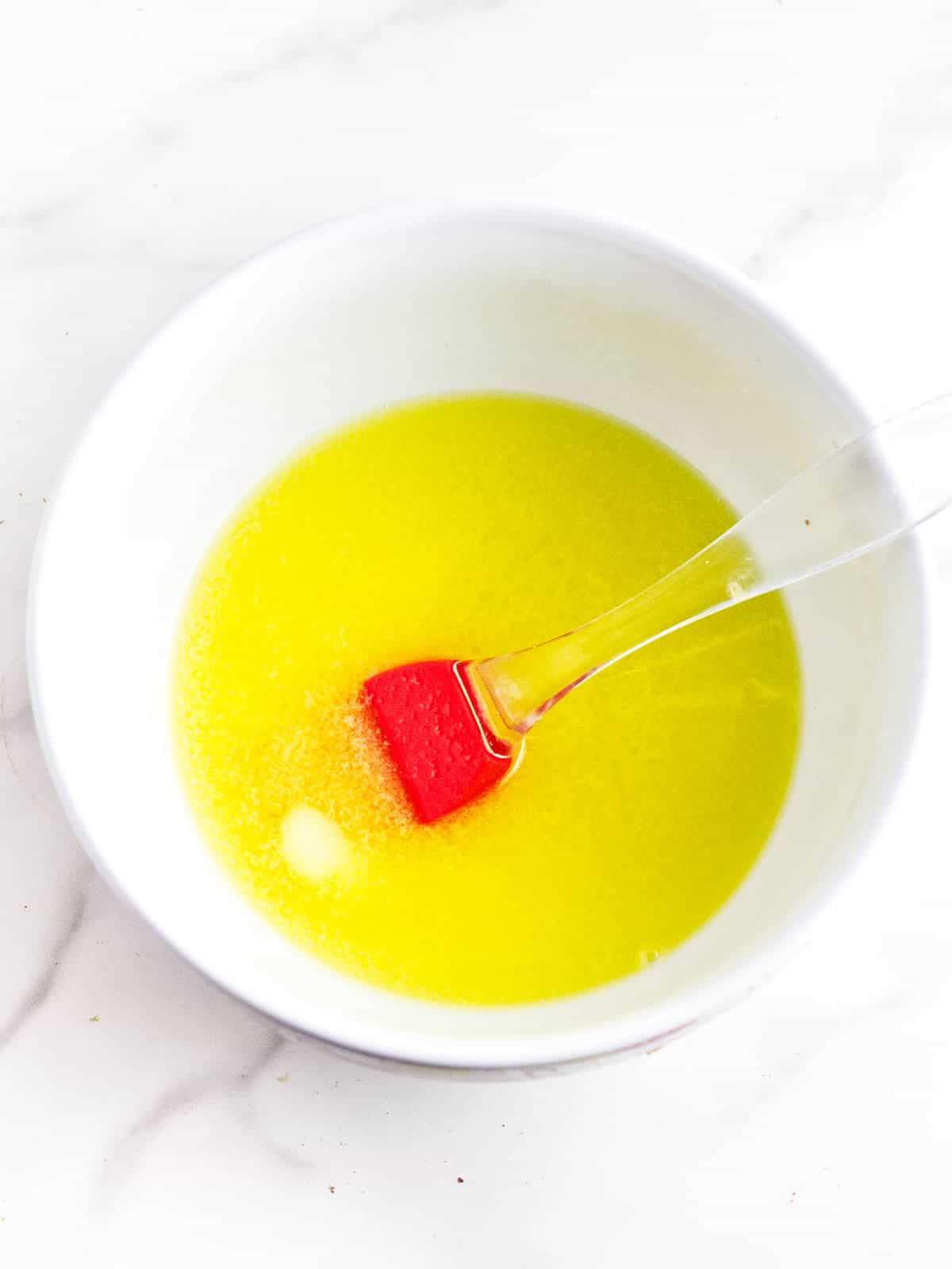 Melted butter in a bowl with a brush.