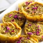 pistachio baklava garnished with chopped pistachios and rose petals.