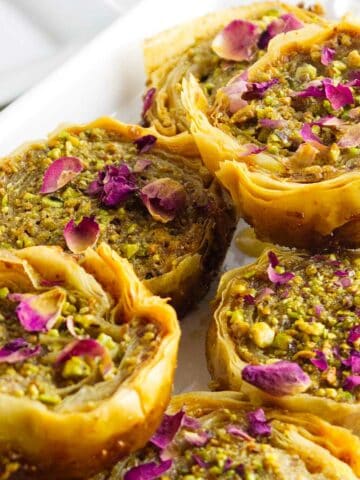 pistachio baklava garnished with chopped pistachios and rose petals.