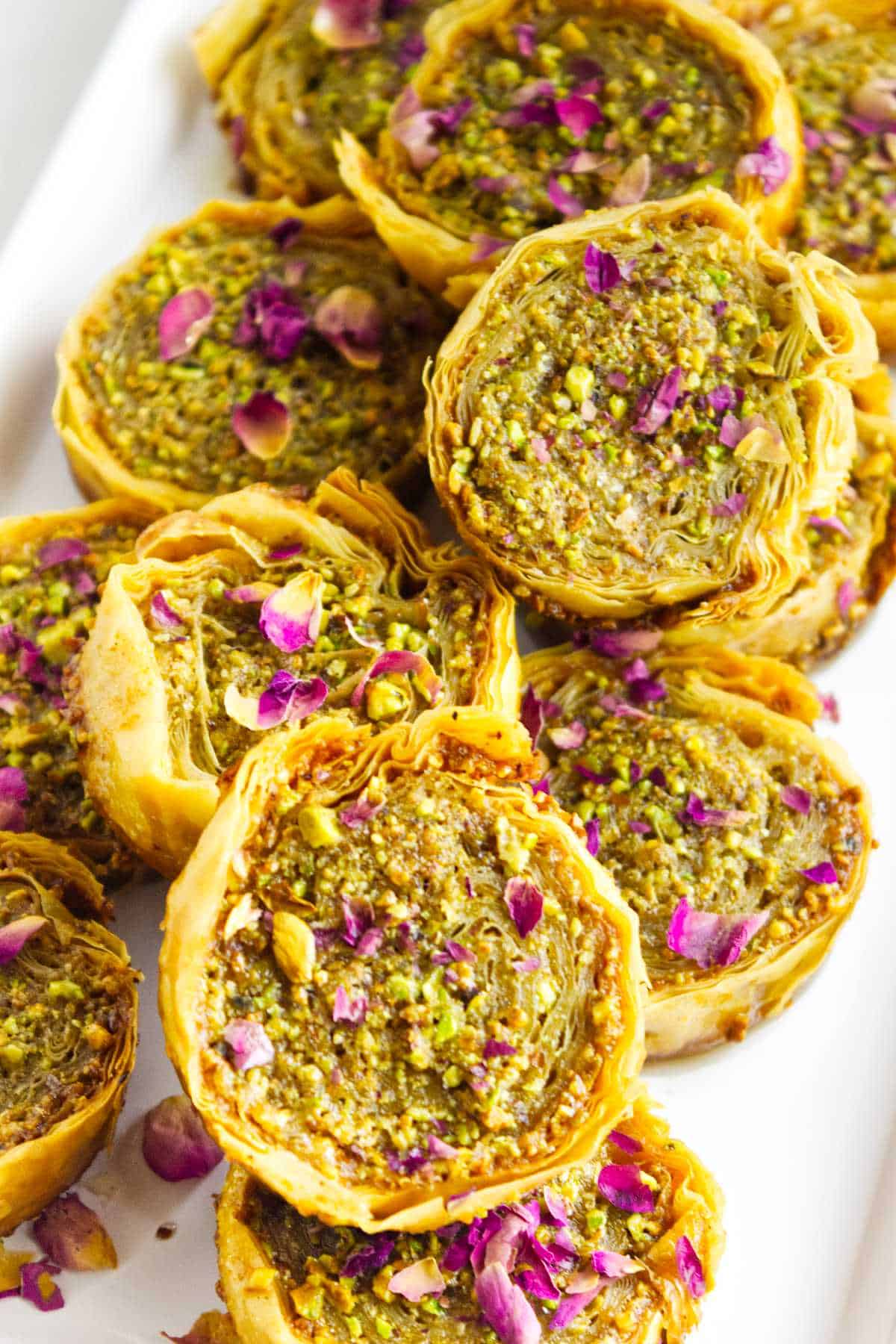 pistachio baklava garnished with chopped pistachios and rose petals.