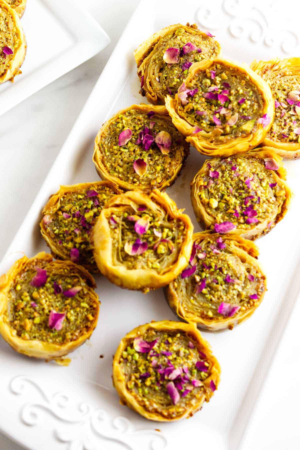 pistachio baklava garnished with chopped pistachios and rose petals.