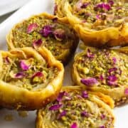 pistachio baklava garnished with chopped pistachios and rose petals.