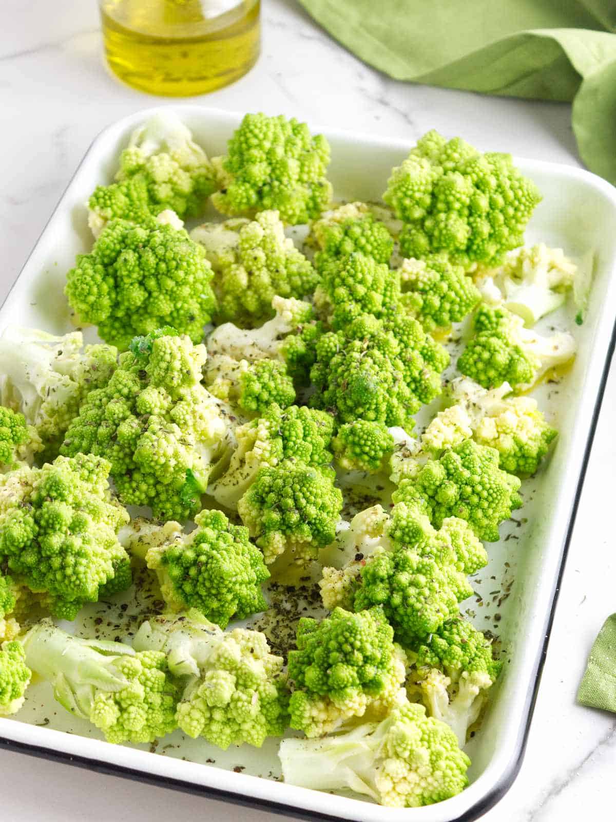 romanesco florets on a baking sheet drizzled with olive oil and black pepper.