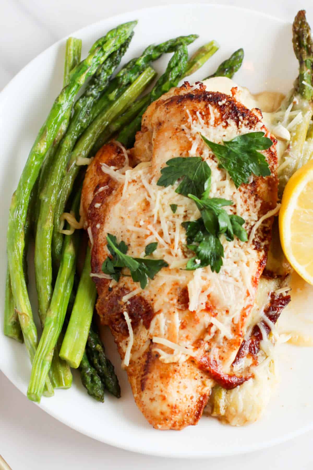 plate with roasted asparagus and cheese stuffed chicken breasts.