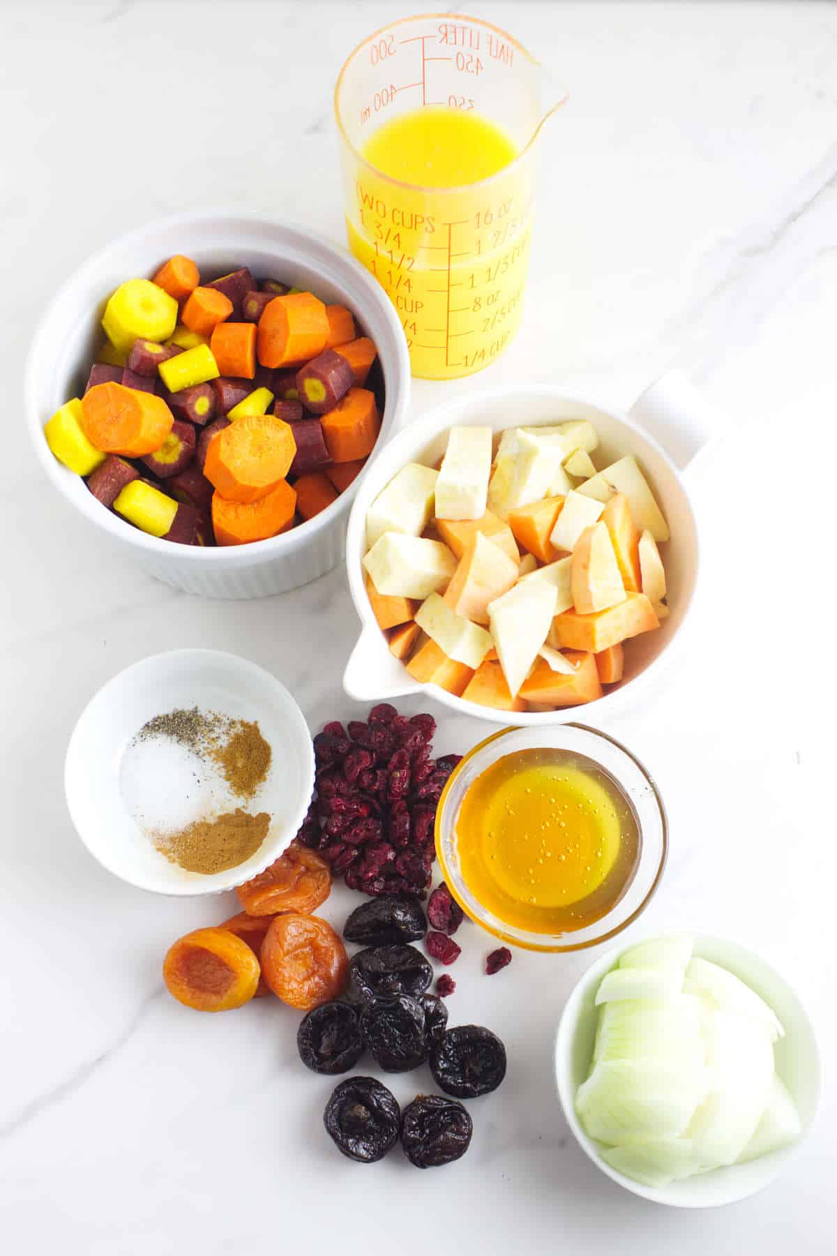 ingredients for making a rainbow tzimmes with carrot, sweet potato, and dried fruits.