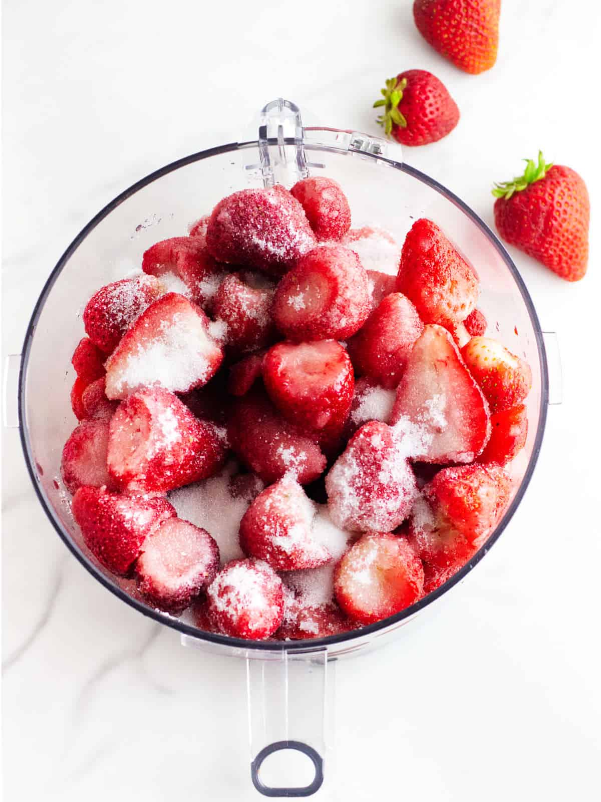 Sugar added to food process full of strawberries.